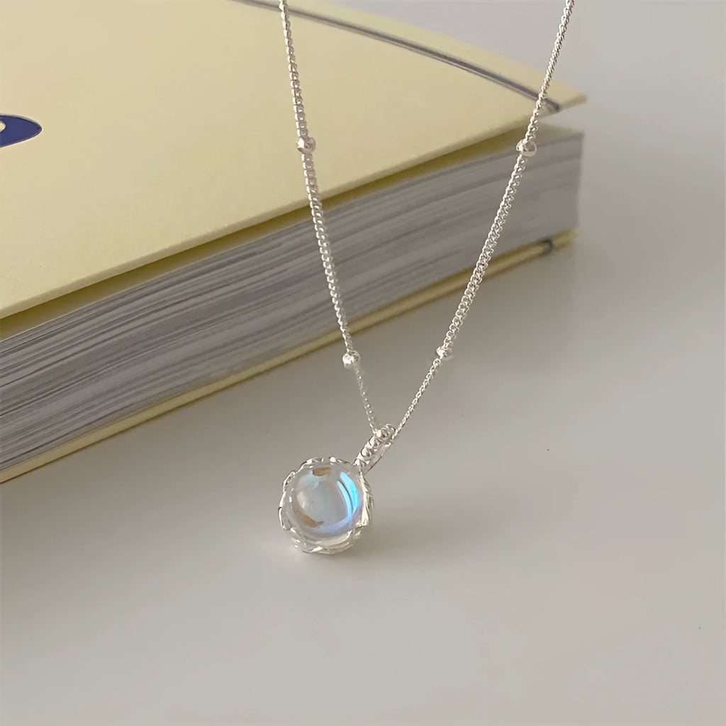 Silver women's necklace with round ornamental stone geometric pendant on a curb chain.