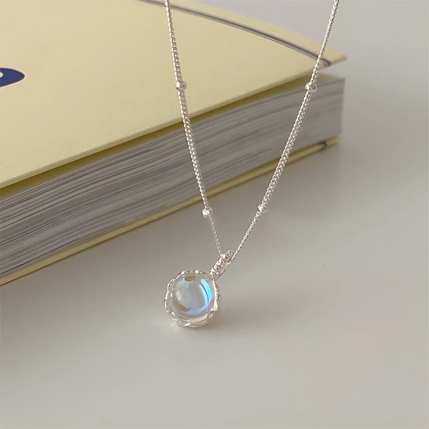 Silver women's necklace with round ornamental stone geometric pendant on a curb chain.