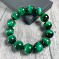 Natural green tiger eye stone bracelet with polished spherical beads in geometric design on wrist.