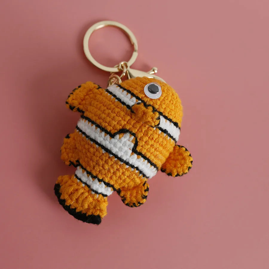 Crocheted wool fish keychain in cartoon ugly fish doll style with key ring, shown in orange, blue or pink