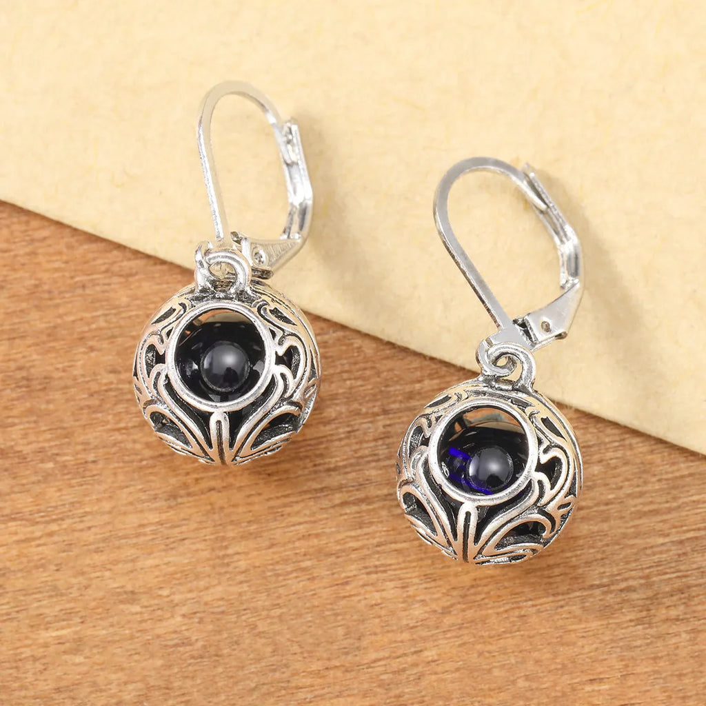 Silver geometric earrings with blue gemstone pendants and hollow engraving details