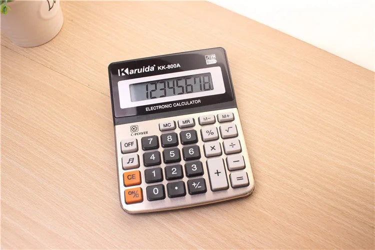 Compact silver aluminium desktop pocket calculator on a desk surface, approximate dimensions 14.5 x 11 x 2.5 cm