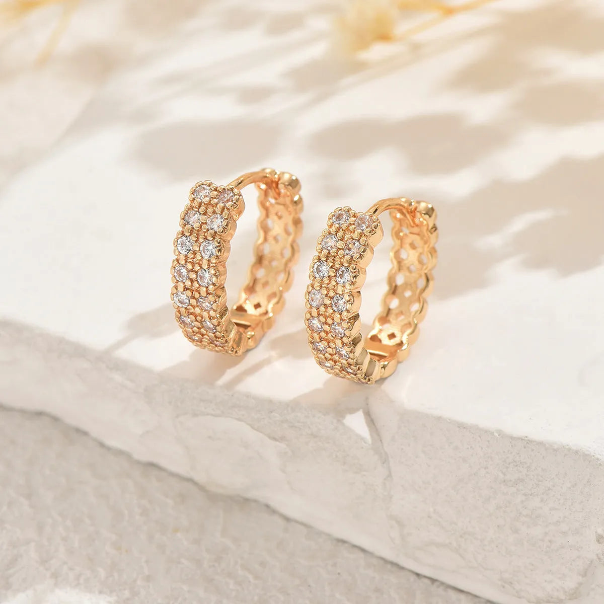 A pair of copper geometric pattern ear studs with round, dot, and ring design elements.