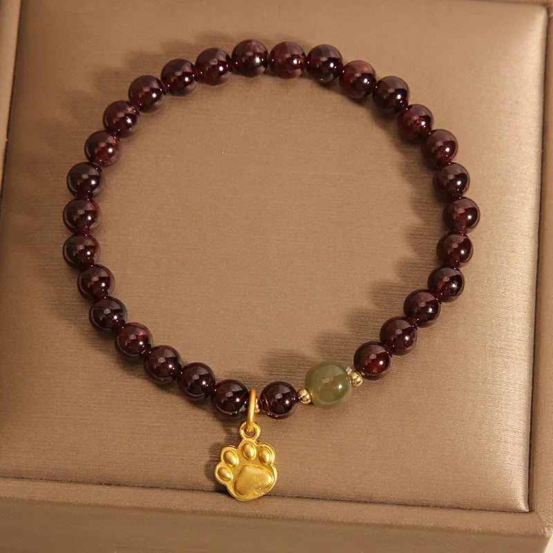 Women's crystal bracelet with a cat's paw garnet design on a polished metal setting.