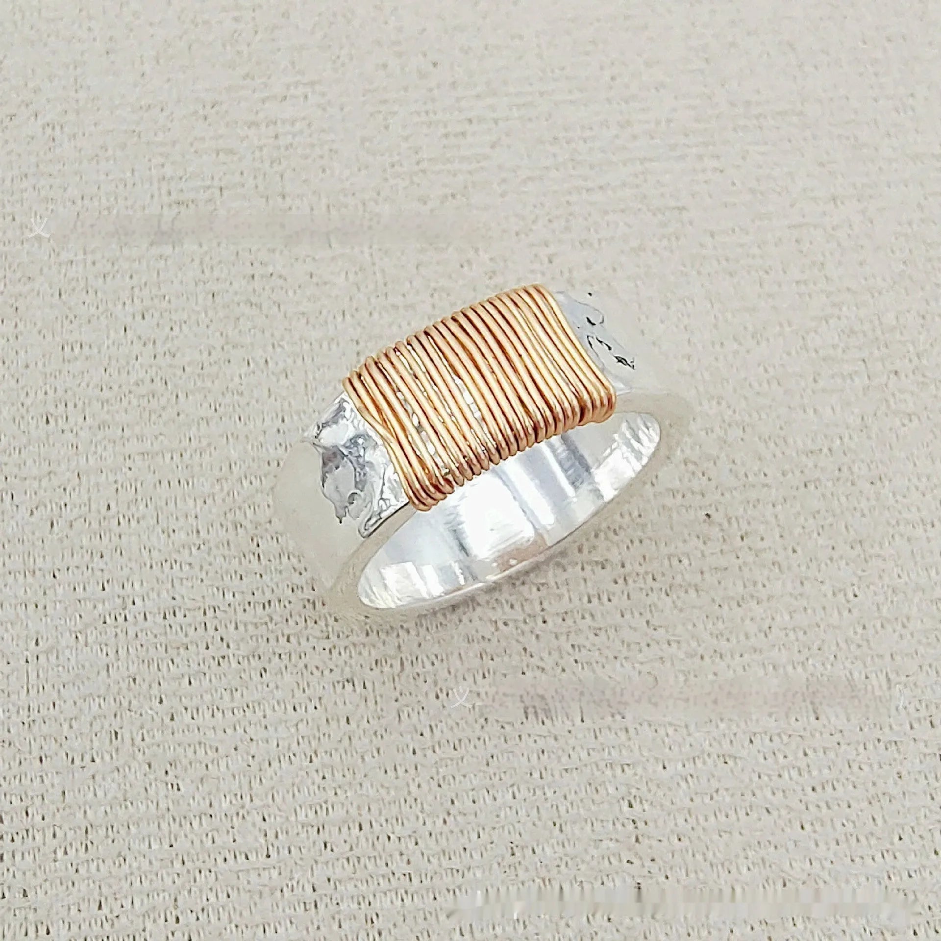 Copper wide face geometric ring bracelet in silver gold coil colour on a plain background.