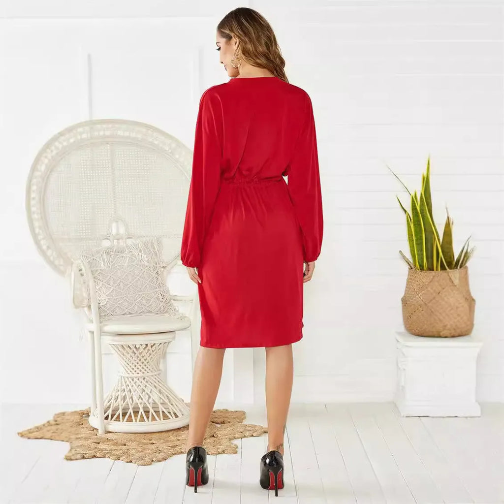 A woman wearing a red mid-length A-line cardigan dress with an elasticated waist and long sleeves.