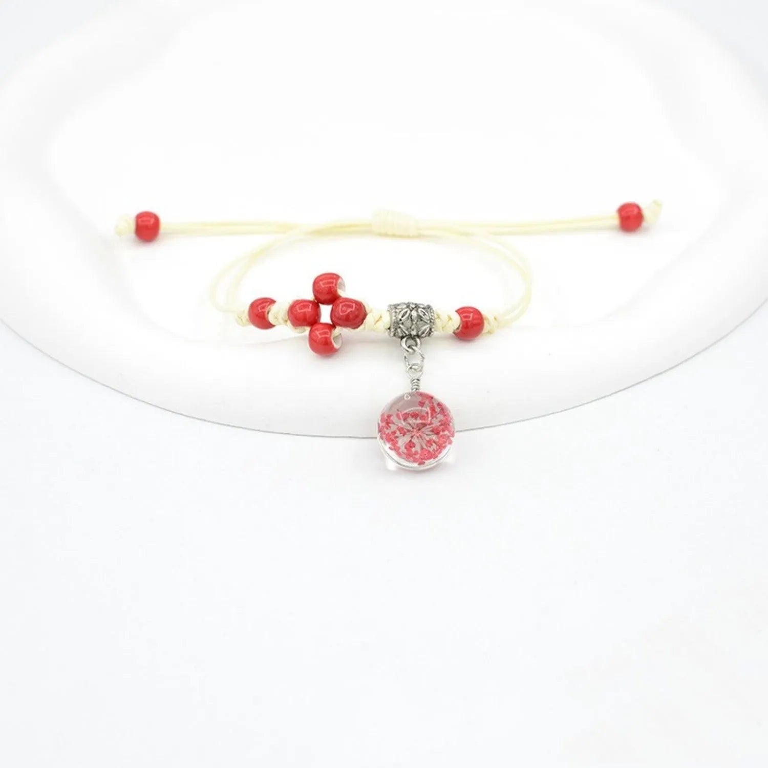 Close-up of a hand-woven glass dried flower bracelet with large colourful beads on a wrist.