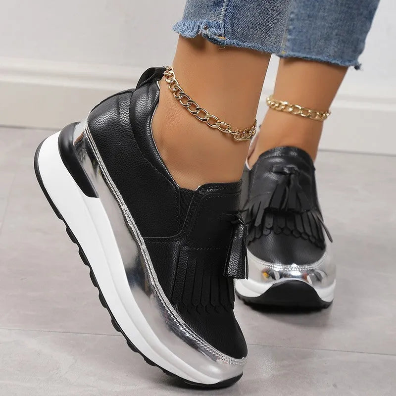 Women's black casual platform shoes with a muffin wedge heel and a decorative tassel.