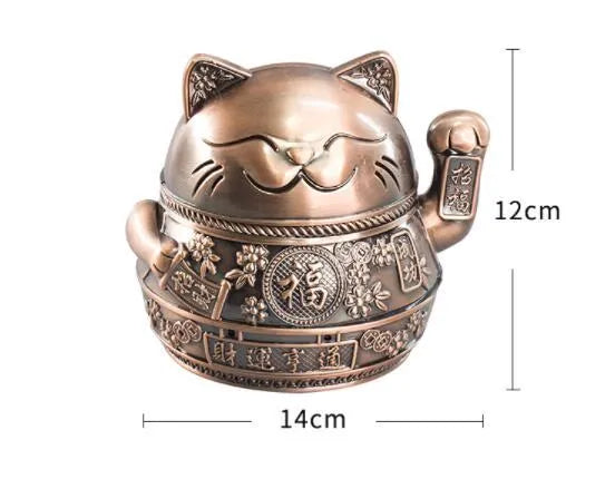 Zinc alloy Lucky Cat ashtray with cover in a gold-black finish on a table