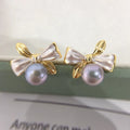 Two-tone bow pearl stud earrings in white or gray with flat circle shape