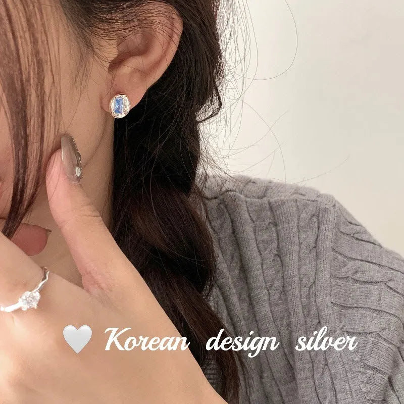 S925 sterling silver earrings with geometric heart-wrapped design and oval blue diamond elements