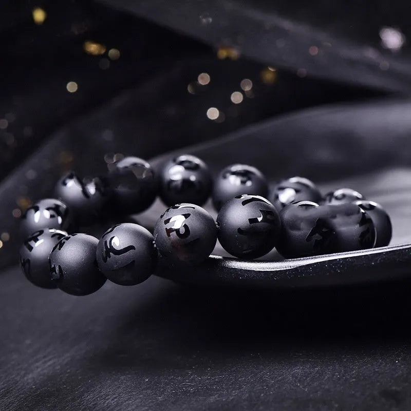 Natural frosted black agate bracelet engraved with a Sanskrit mantra, showing stone-coloured glaze.