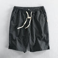 Man wearing black and white striped cotton casual shorts with a loose straight fit.