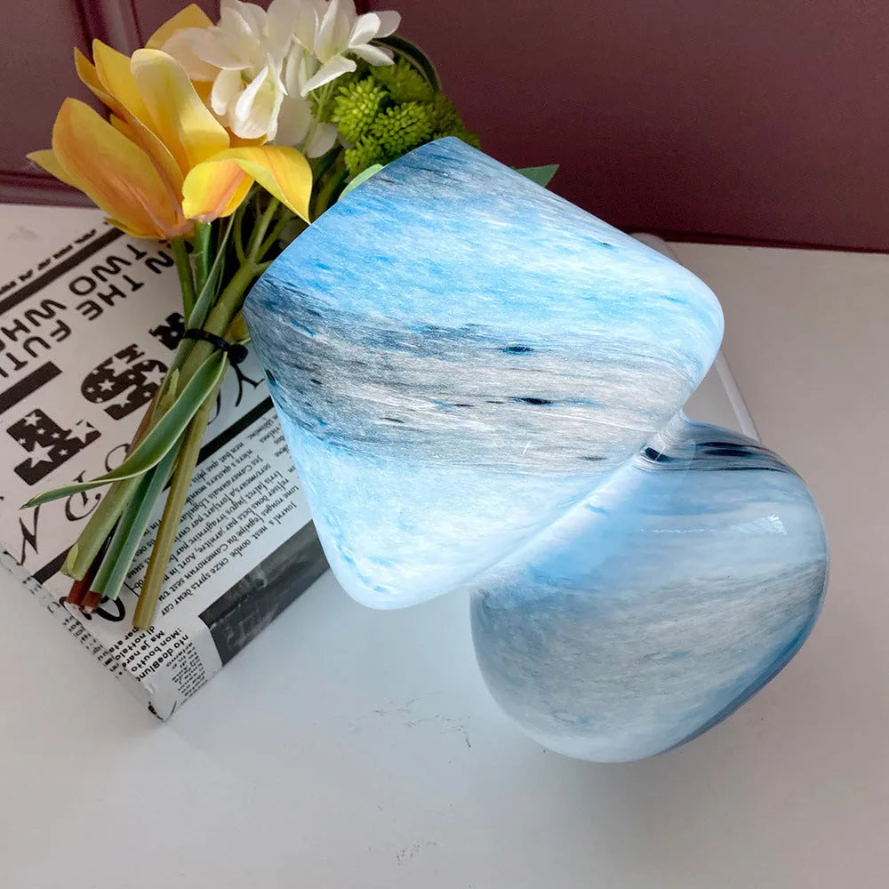 Handmade glass mushroom table lamp in colour finish, 15cm diameter, on a bedside table.