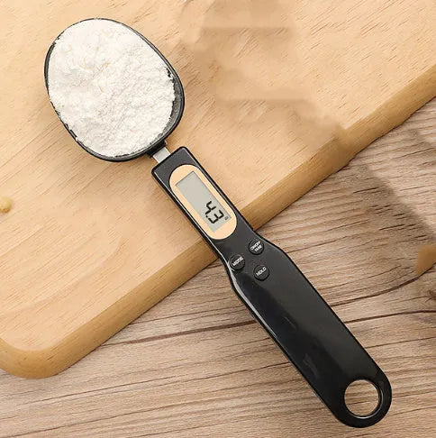 White electronic digital spoon scale with LCD display on a kitchen counter.