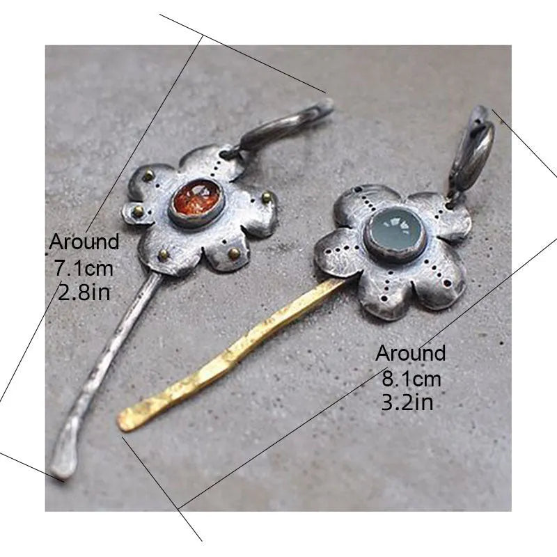A pair of long, geometric flower-shaped retro earrings in two contrasting metallic colours with an asymmetrical design.