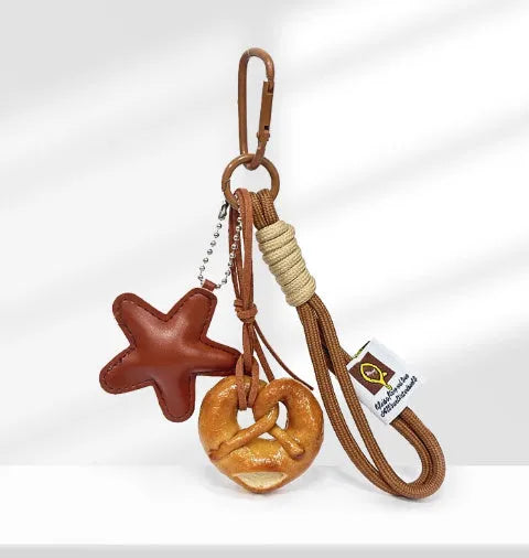 Handmade soda bread style handbag pendant with brown strap, showing cartoon croissant design.