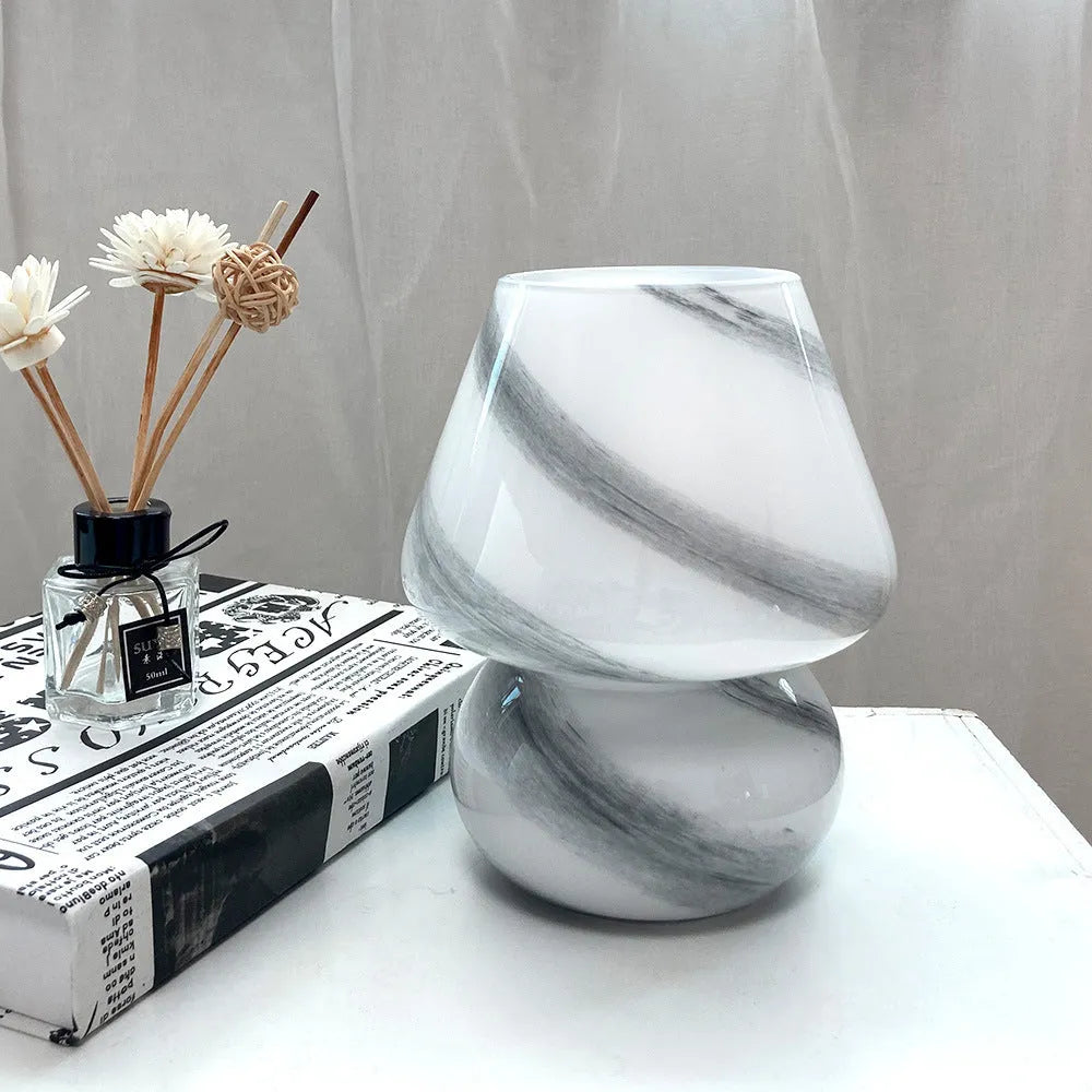 Handmade glass mushroom table lamp in colour finish, 15cm diameter, on a bedside table.