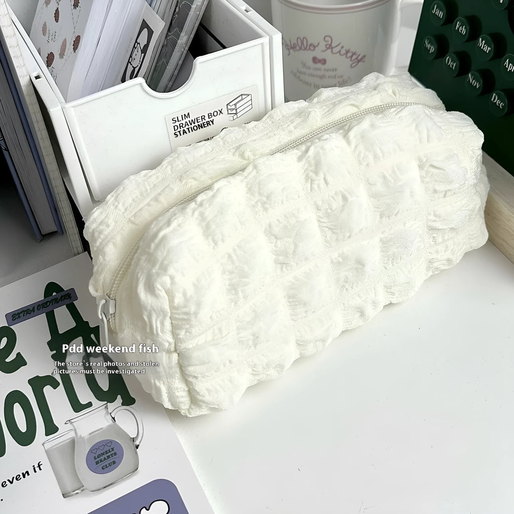 Beige fabric pencil case with a rounded cream puff design next to black version.