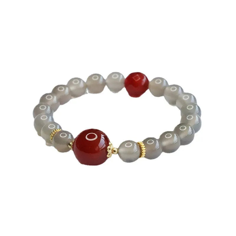 Close-up of a bracelet with smoky purple and red agate geometric beads on a white background.