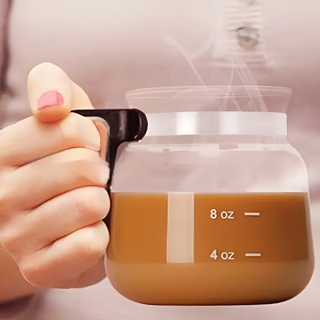 Transparent borosilicate glass coffee maker with black silicone cover on a stovetop