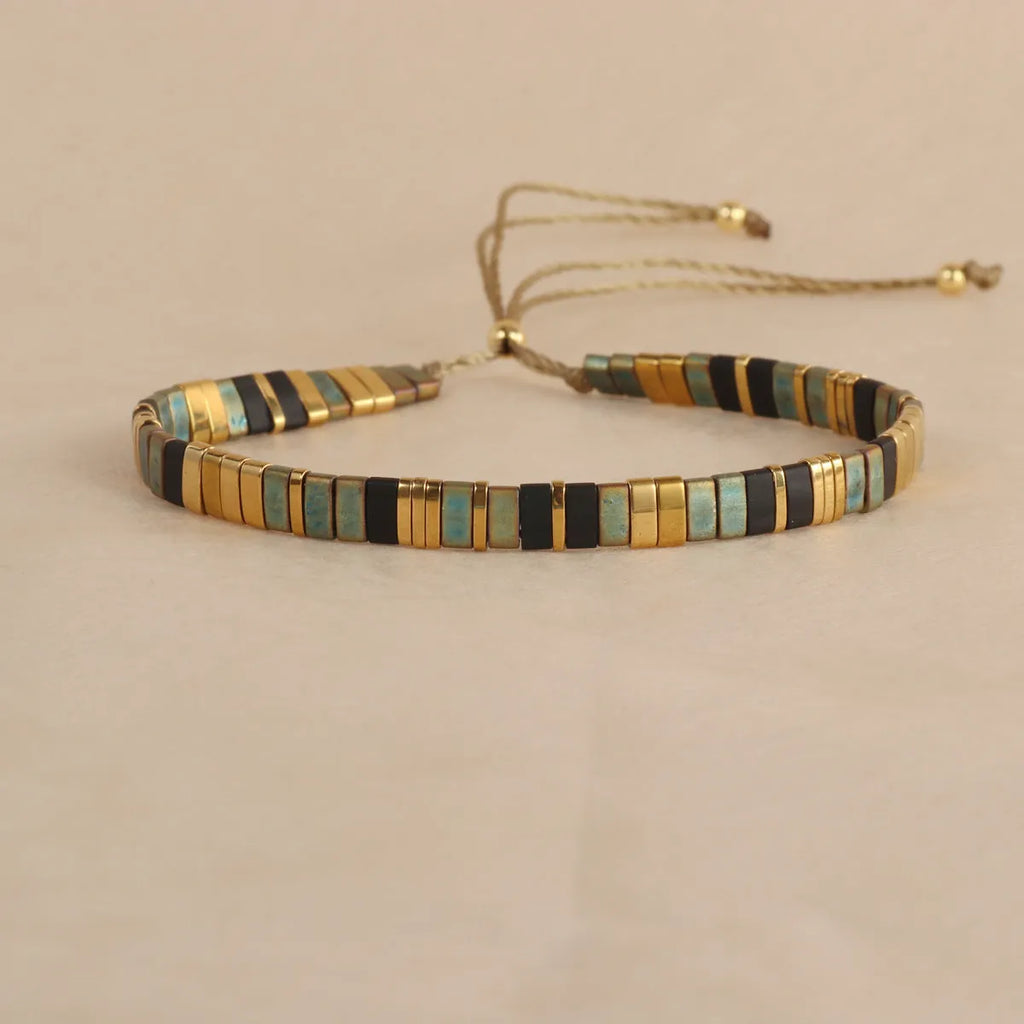 Geometric glass beaded bracelet in milky white, black, green, blue, or red on a plain background.