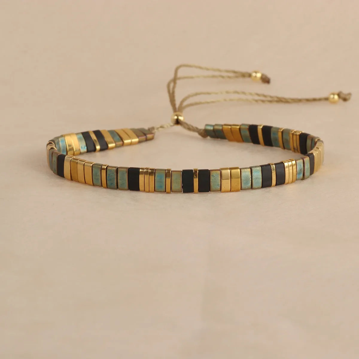 Geometric glass beaded bracelet in milky white, black, green, blue, or red on a plain background.