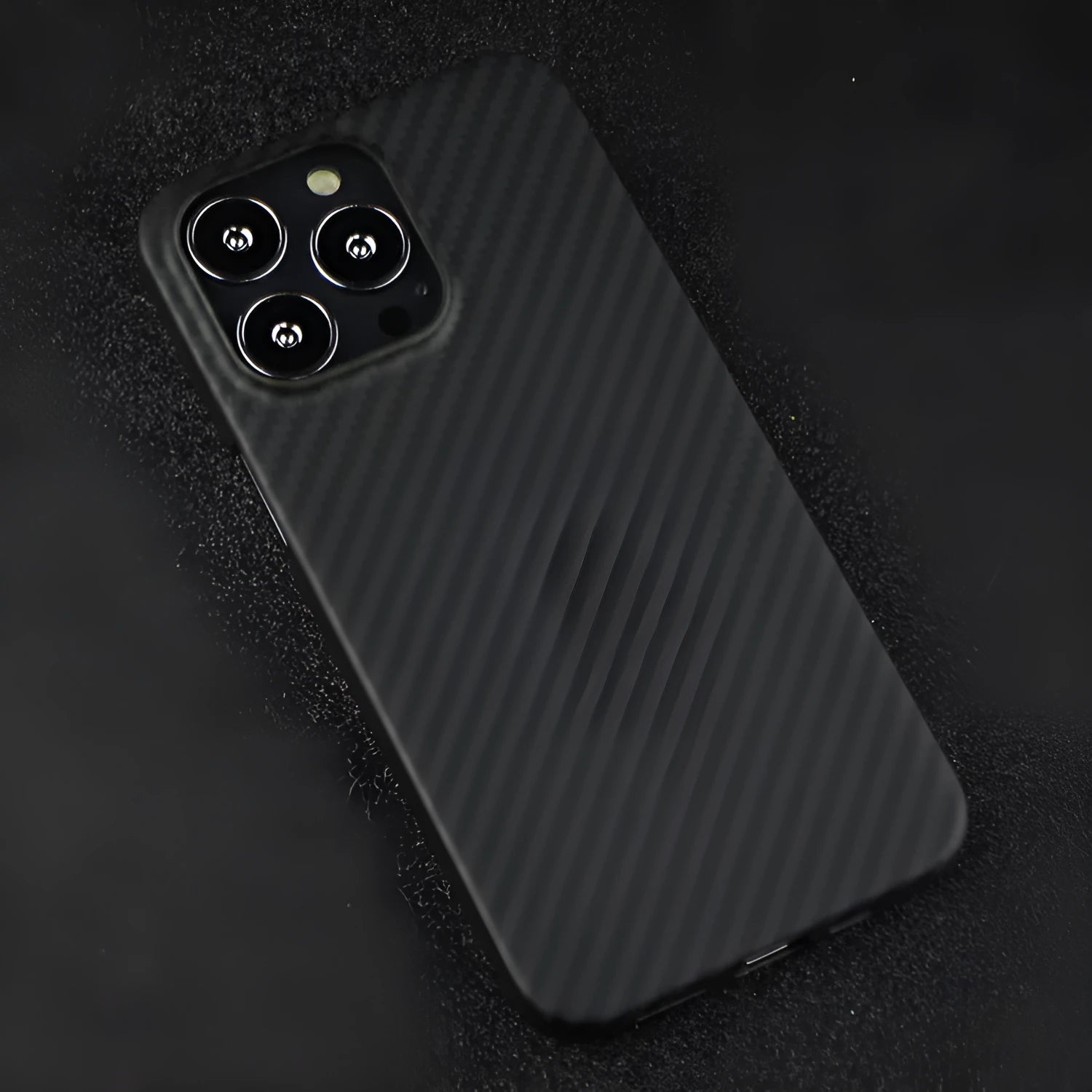 Matte black Kevlar fibre iPhone case with textured back, shown next to an iPhone.