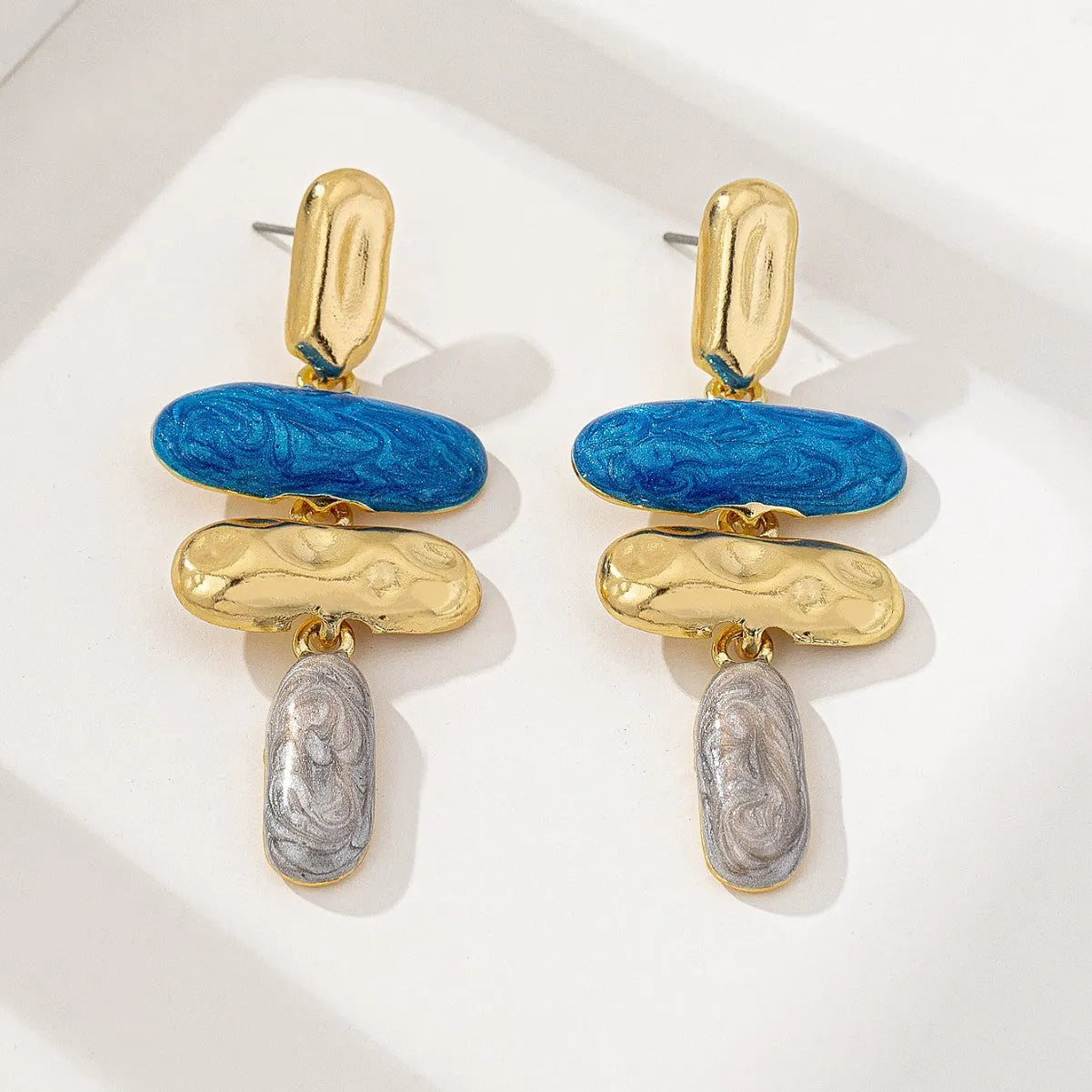 A pair of geometric multicolour stud earrings for women on a plain background.