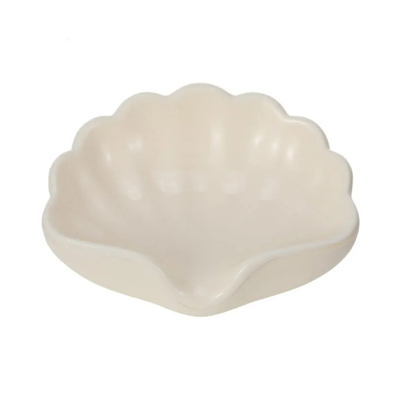 White plastic shell-shaped soap dish with drainage holes on a bathroom countertop