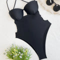 Black solid colour one-piece swimsuit for women on a hanger.