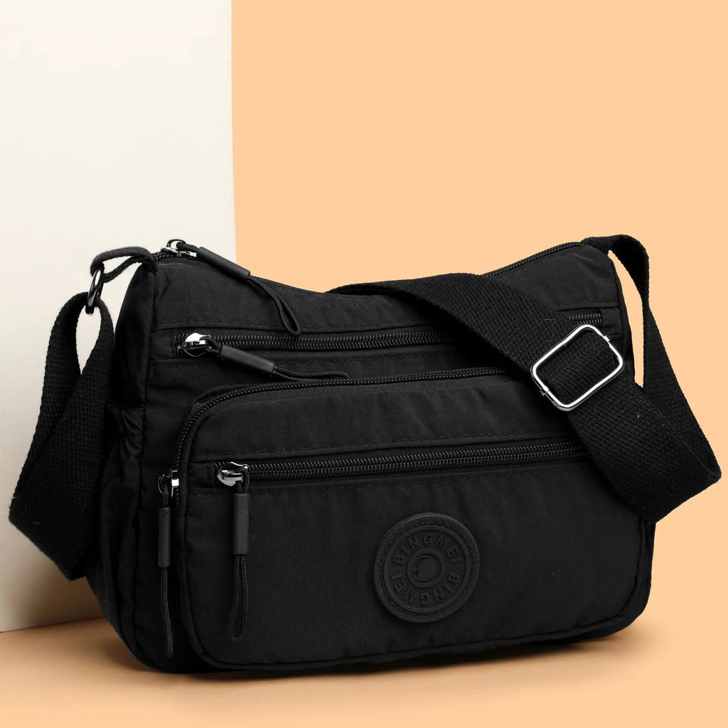 Water-repellent nylon crossbody cloth bag in black, grey or red with internal zipper compartments