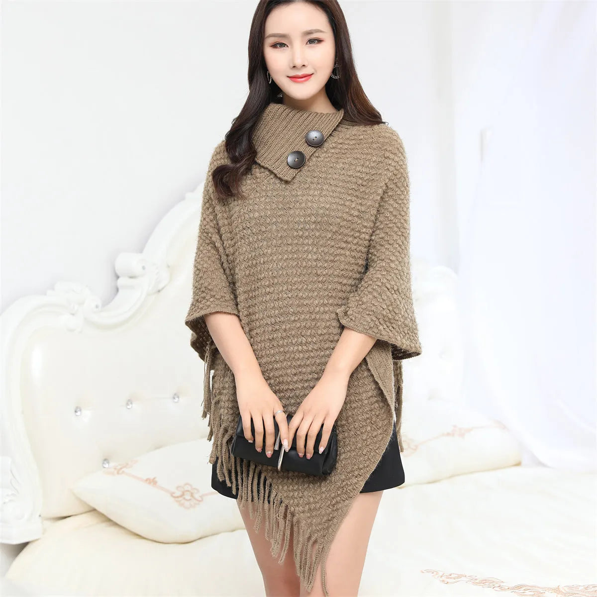 Sleeveless dotted-pattern cloak shawl in acrylic knitwear, shown in apricot colour.