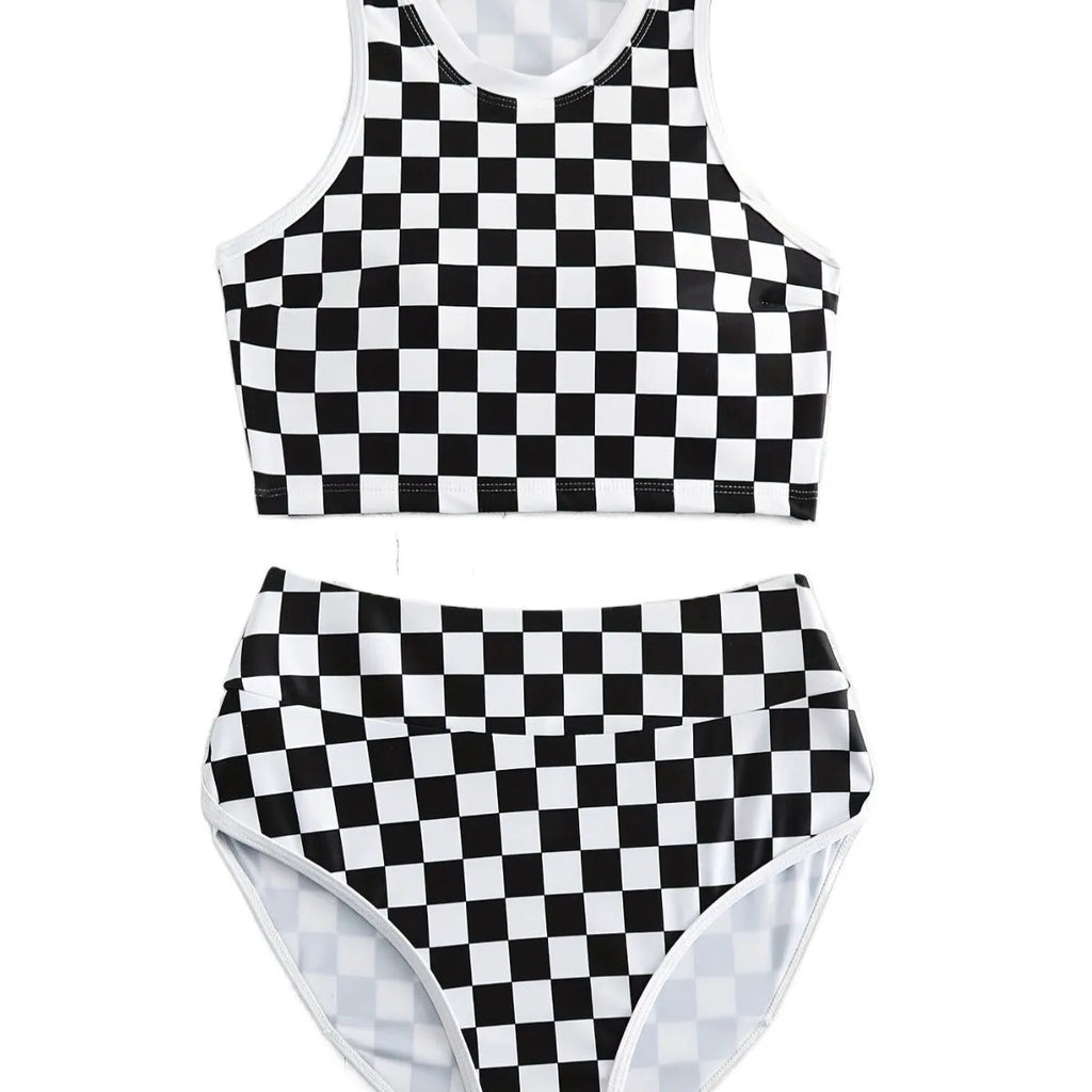Adult woman wearing a black and white checkerboard print one-piece swimsuit with suspender straps and a backless sporty design.