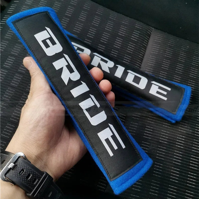 Pair of black car safety belt shoulder pads showing sponge cloth padding and embroidery detail
