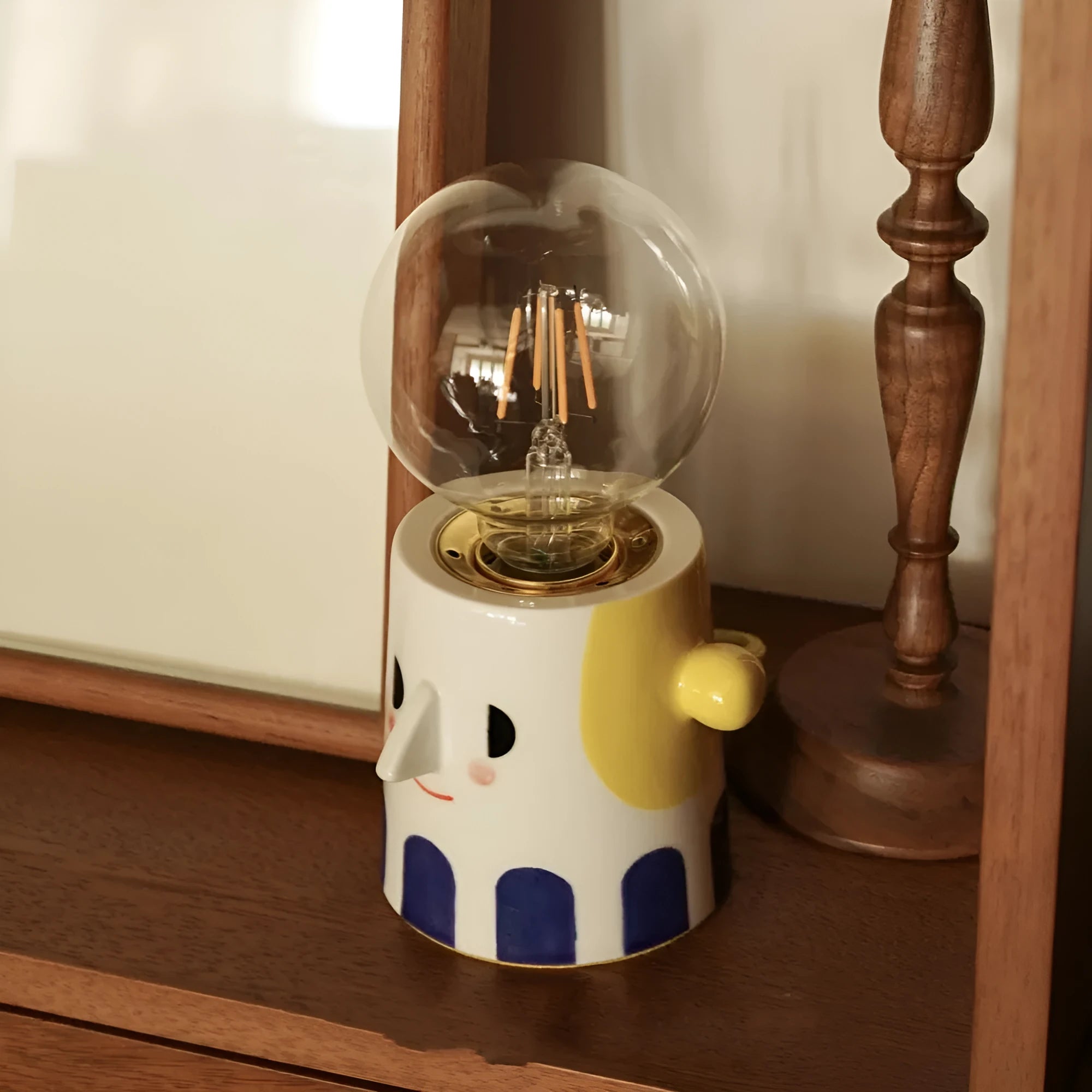 Handmade ceramic bedside lamp with ball headlight colour finish on a table.