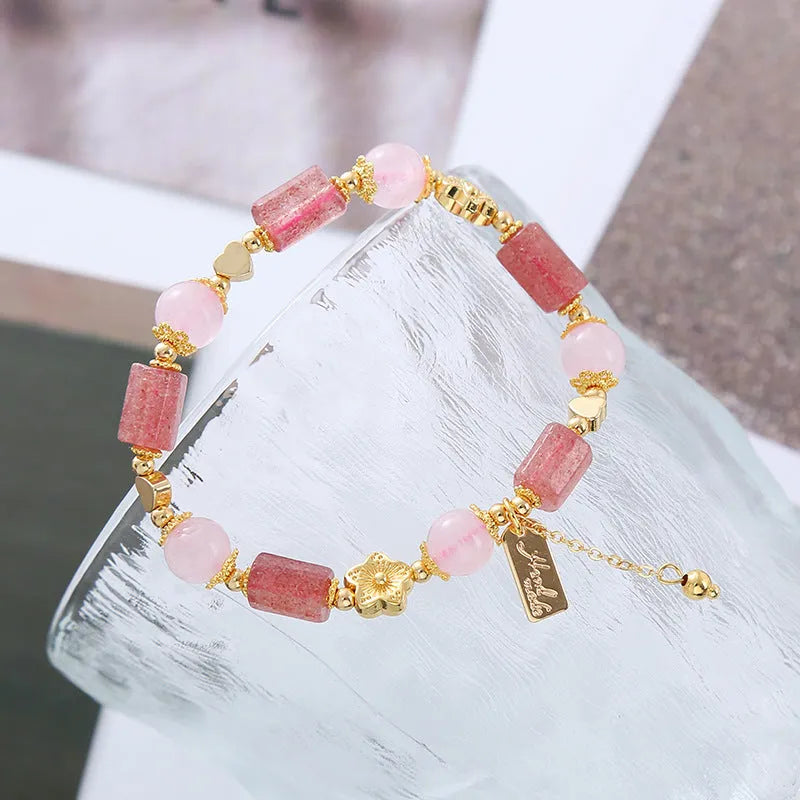 Pink strawberry crystal bracelet with star-shaped beads and a small heart charm on a white background