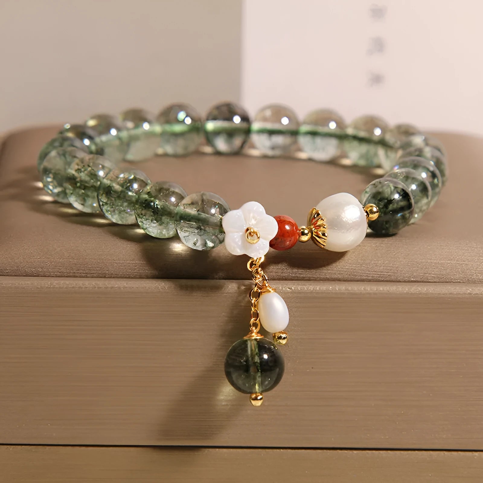 Green phantom quartz crystal bracelet with shell flower charms on wrist