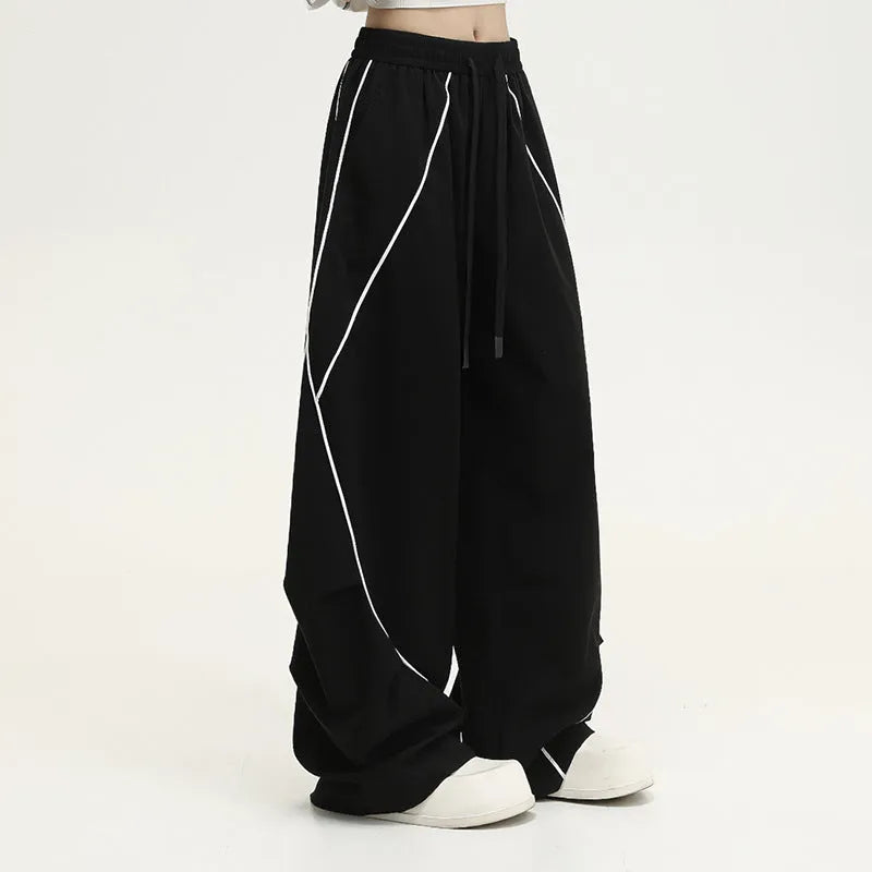 Black striped wide-leg sports pants with pleated detail on a mid-waist, loose fit.