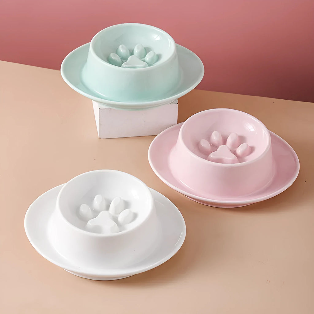 Green ceramic slow feeder pet bowl with internal maze pattern and raised basin design on a wooden floor.