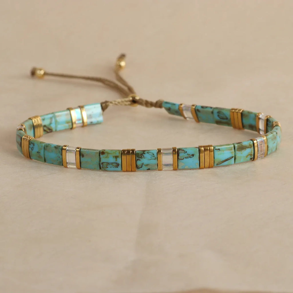 Geometric glass beaded bracelet in milky white, black, green, blue, or red on a plain background.
