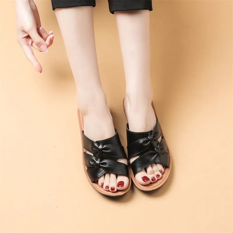 Women's beige cowhide slippers with a soft sole and synthetic leather lining, shown in a sandal style.