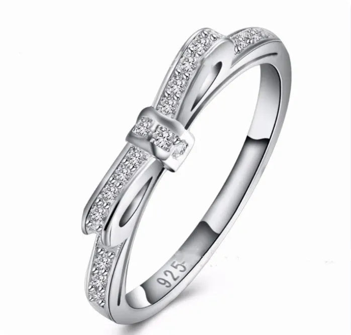A silver couple-style ring with a bow shape decorated with rhinestones and zircon crystals.
