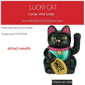 Small yellow solar-powered Maneki Neko lucky cat decoration waving, shown on a car dashboard.