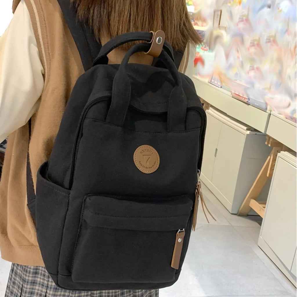Black retro-style Oxford cloth backpack with curved shoulder straps and sewing thread detail.