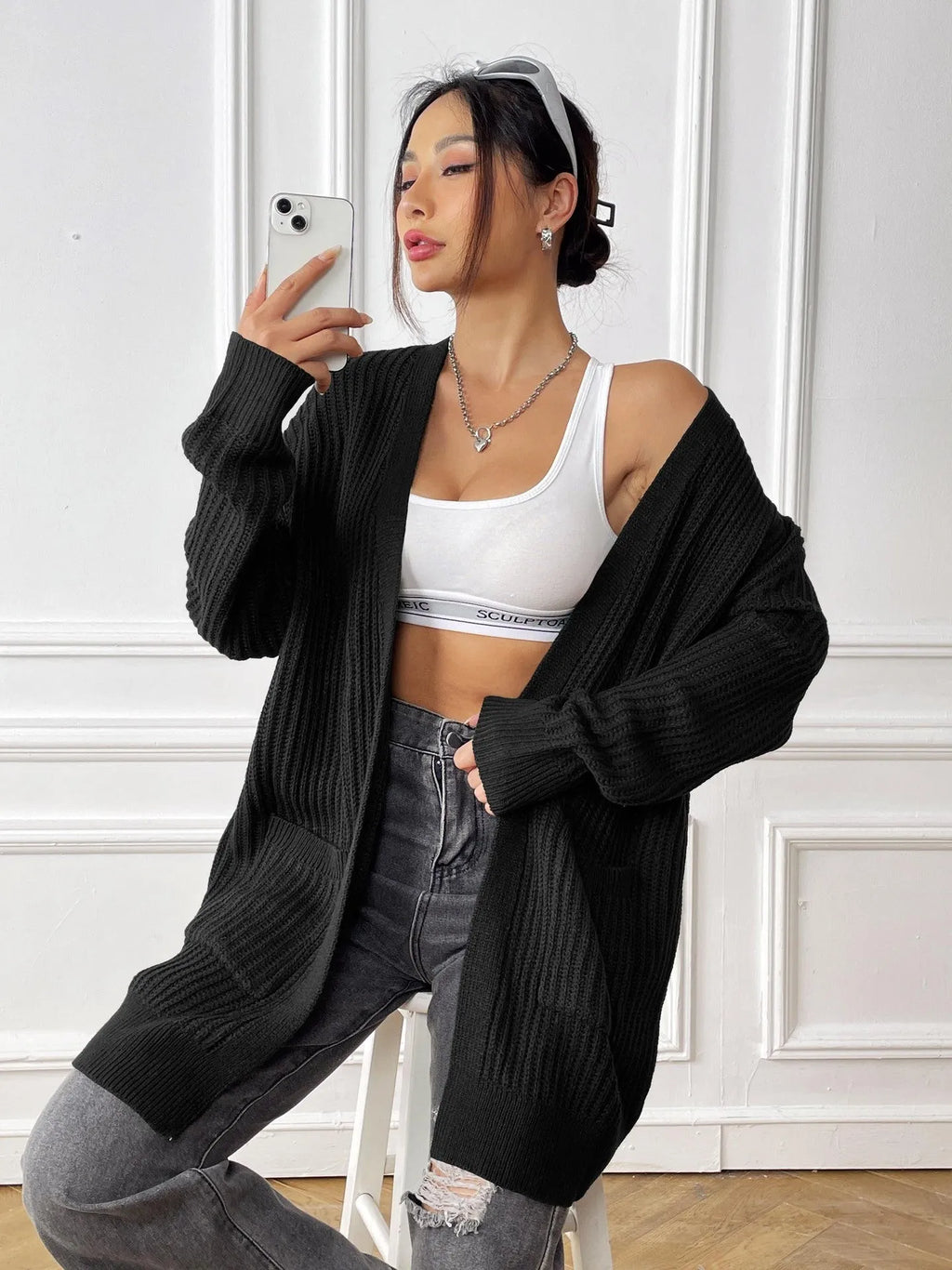 A woman's loose-fit acrylic cardigan in dark green with long sleeves and two front pockets.