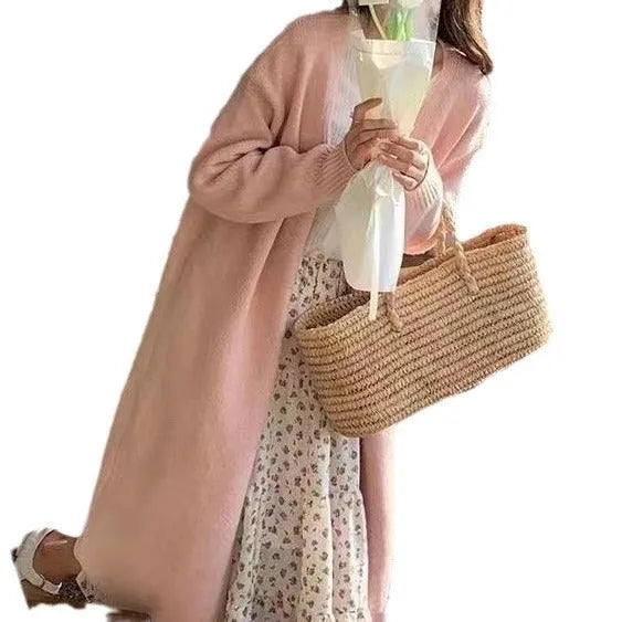 A woman wearing a khaki coloured, mid-length V-neck knitted cardigan with long sleeves.
