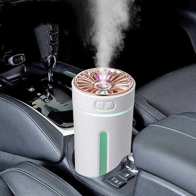 Black and white portable USB rechargeable car humidifier with colourful LED lights on a desk.