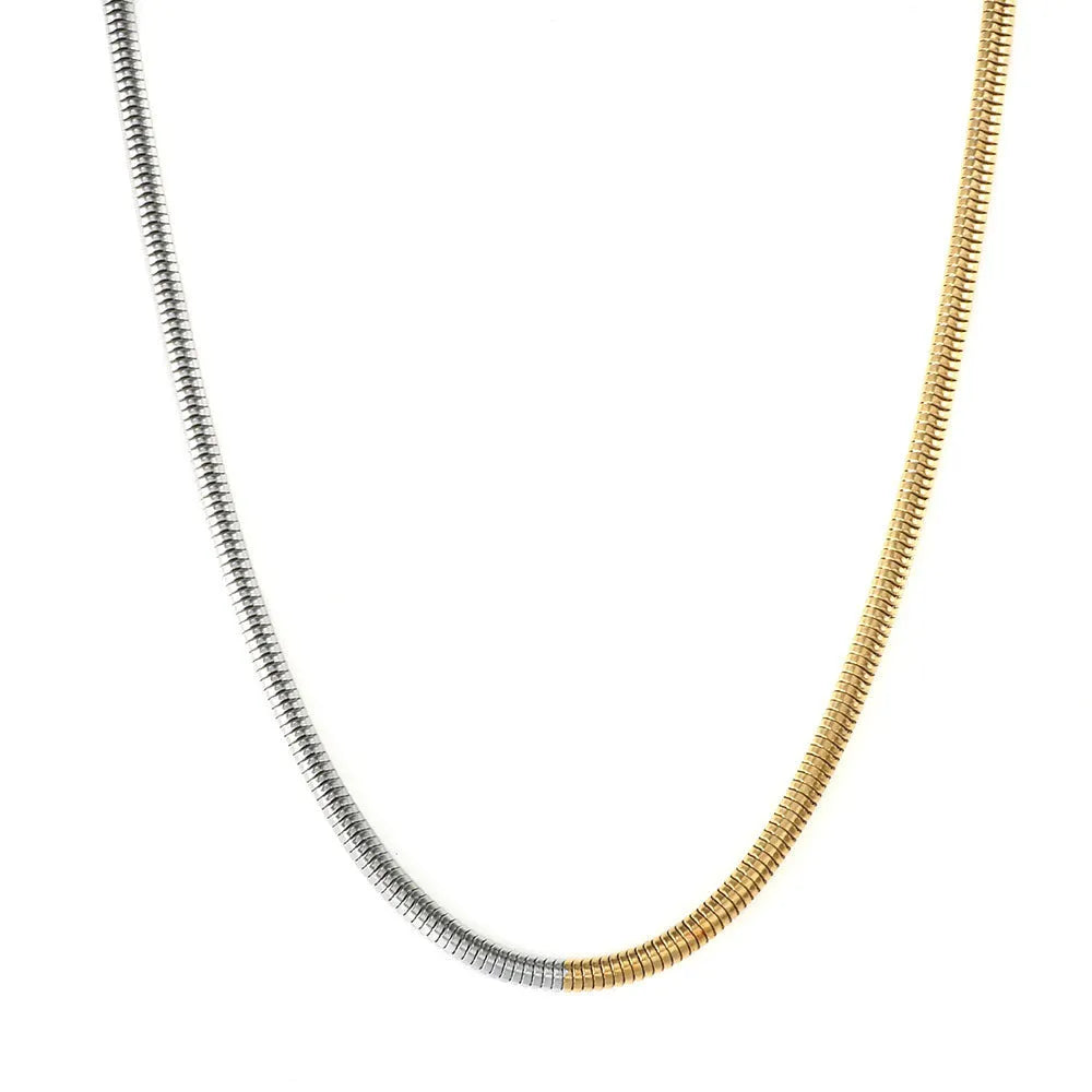 Close-up of a woman's golden 3mm wide snake bones chain necklace with geometric links.