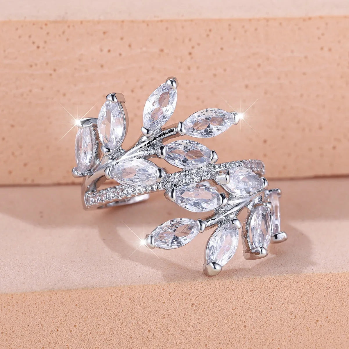 Adjustable copper leaf-shaped ring with zircon stone accents on a hand.